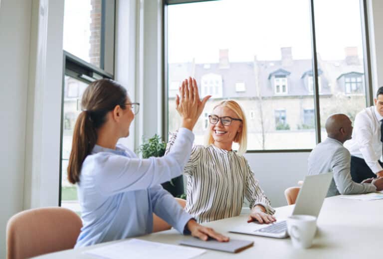 Smiling businesswomen high fiving each other in an office boardroom